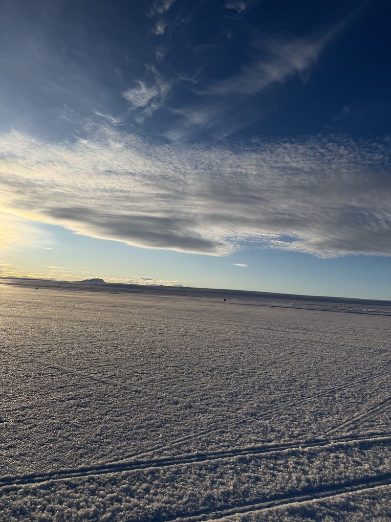 The Antarctic plain at low sun, blue ice stretching to the horizon